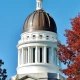 Maine state capital building behind trees
