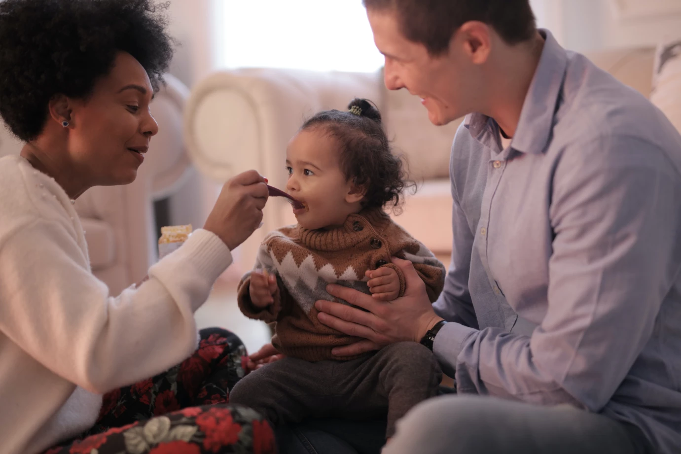 Two adults feeding a baby.